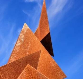 sculpture_quatre_triangles_en_cuivre_rouille_sous_un_ciel_bleu
