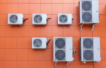 mur orange parcouru de pompes à chaleur et systèmes de climatisation
