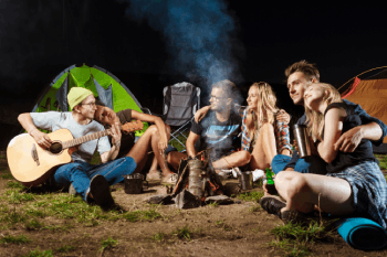 amis heureux autour du feu devant un campement
